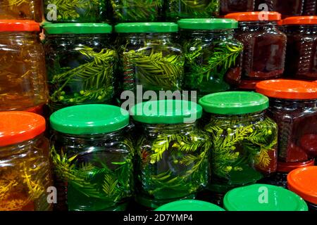 Pots en verre avec différents types de miel avec des feuilles de sapin et de tilleul sur le marché. Banque D'Images