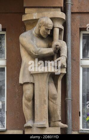 Allégorie de l'industrie représentée dans le groupe sculptural par le sculpteur tchèque Karel Kotrba (1924), au-dessus de l'entrée de l'ancien bâtiment de la Banque centrale d'épargne de l'Association légionnaire tchécoslovaque (Ústřední záložna Družiny československých legionářů) dans la rue Myskova à Nové Město (Nouvelle ville) à Prague, République tchèque. Banque D'Images