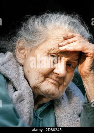 Vieille femme. Portrait d'une femme très vieille et fatiguée de la vie froissée à l'extérieur avec une main près de son visage Banque D'Images