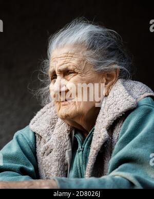 Vieille femme. Portrait d'une femme très vieille et fatiguée de la vie froissée à l'extérieur près du mur de sa maison Banque D'Images