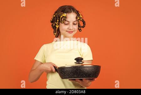 chef confiant. enfant joyeux avec des pillards. ménage de l'enfance. petite femme tient la casserole. cuisine dans la cuisine. concept de ménage. cuisine pour enfants à la maison. bonne enfance. Banque D'Images