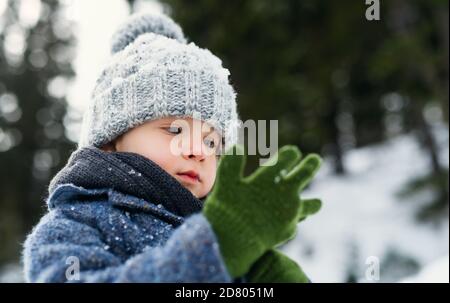 Vue de face d'un petit enfant debout dans la neige, vacances dans la nature d'hiver. Banque D'Images