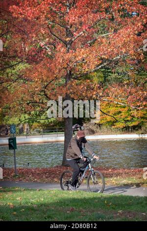 COULEURS D'AUTOMNE. Un vélo portant un masque se déplace autour du lac dans le parc de Kissena lors d'une matinée d'automne fraîche. Banque D'Images