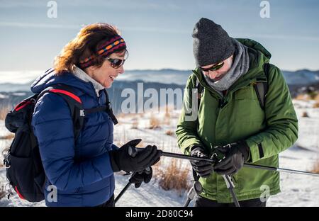 Des randonneurs en couple avec des bâtons de marche nordique dans la nature enneigée de l'hiver. Banque D'Images