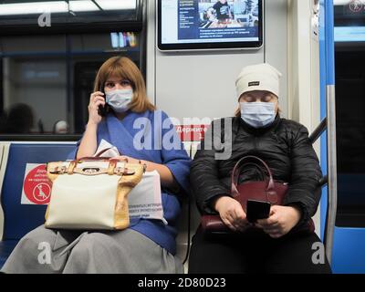 Moscou. Russie. 13 octobre 2020. Deux femmes dans une voiture de métro communiquent sur un smartphone. Sur le visage des passagers sont des masques de protection. Inscriptions Banque D'Images