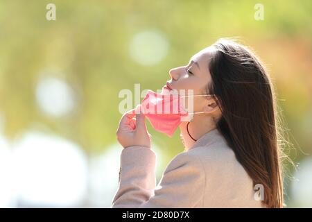 Profil d'une femme détendue prenant le masque respiration fraîche air dans un parc à l'époque du coronavirus Banque D'Images