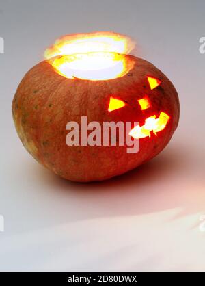 citrouille d'halloween. un halo se sépare des entrailles. Citrouille ronde orange avec visages sculptés grossièrement et lanterne en verre à l'intérieur Banque D'Images