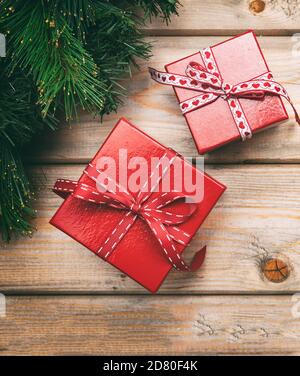 Boîtes-cadeaux de Noël couleur rouge avec rubans et guirlande d'arbres de Noël sur fond de bois, vue du dessus Banque D'Images