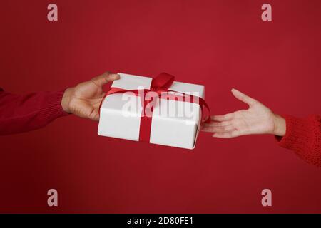 Bonne année et Joyeux Noël. Un mari afro-américain donne une boîte avec cadeau à sa femme en chandail Banque D'Images