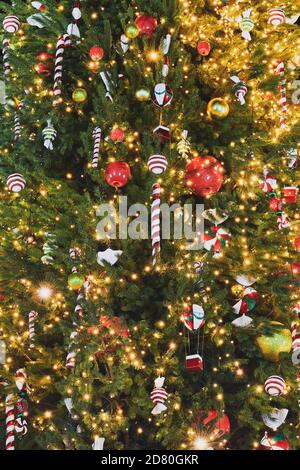 Magnifique sapin de Noël décoré de guirlandes, de bonbons de Noël et de différentes boules colorées. Décorations du nouvel an. Arrière-plan vertical. Banque D'Images