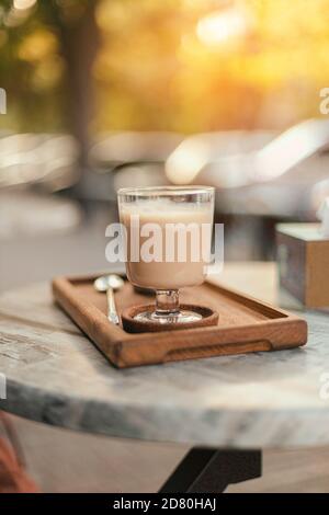 Latte ou café avec boisson au lait sur un plateau en bois sur une table de rue dans le parc. Orientation verticale de la photo Banque D'Images