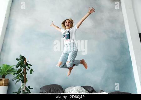 Bonne fille blonde s'amuser dans la chambre sur le lit. Banque D'Images