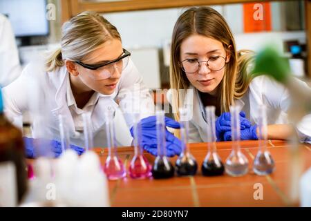 Mignonne chercheuses en blouse de laboratoire blanche travaillant dans le laboratoire Banque D'Images