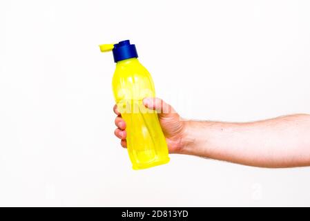 La main de l'homme tient une bouteille d'eau, isolée sur fond blanc. Gros plan. Banque D'Images