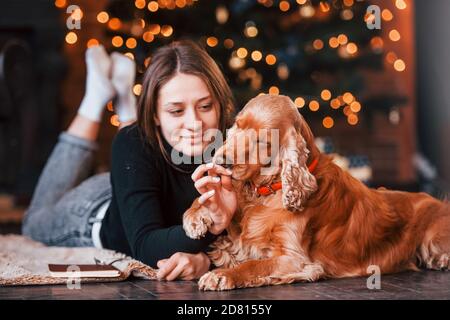 Jeune fille couchée dans la chambre décorée de noël avec elle chien Banque D'Images