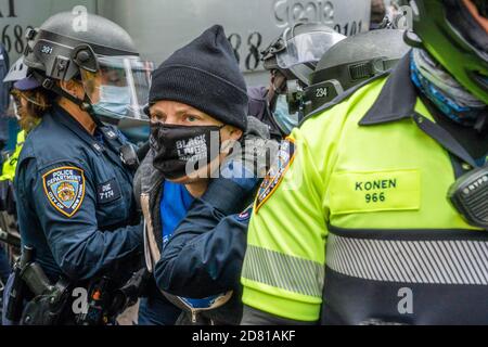 Les policiers du NYPD arrêtent un manifestant anti-Trump pour comportement désordonné durant la manifestation.les partisans du président pro-Trump défilent le long de la 5e avenue avec une caravane de voitures et un énorme drapeau bleu, blanc et noir de Trump. Ils marchent de la Trump Tower sur la 5e Avenue à la 42e rue et de là à Times Square où ils ont rencontré des contre-manifestants. Les manifestants anti-Trump ont lancé des insultes et des objets comme des bouteilles et des œufs remplis de peinture. Il y a eu beaucoup de bagarres entre ces deux groupes et la police a procédé à plus d'une douzaine d'arrestations. Banque D'Images