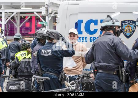 Les policiers du NYPD arrêtent un président partisan de Trump pour une conduite désordonnée pendant la manifestation.les partisans du président pro-Trump marchent le long de la 5e avenue avec une caravane de voitures et un énorme drapeau bleu, blanc et noir de Trump. Ils marchent de la Trump Tower sur la 5e Avenue à la 42e rue et de là à Times Square où ils ont rencontré des contre-manifestants. Les manifestants anti-Trump ont lancé des insultes et des objets comme des bouteilles et des œufs remplis de peinture. Il y a eu beaucoup de bagarres entre ces deux groupes et la police a procédé à plus d'une douzaine d'arrestations. Banque D'Images