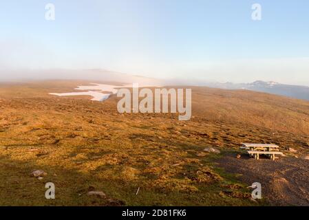 Table de pique-nique vide au sommet d'une montagne couverte avec brouillard au coucher du soleil Banque D'Images