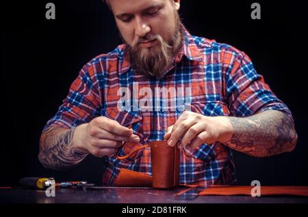 L'homme travaillant avec le cuir forme un nouveau produit de cuir à son atelier Banque D'Images