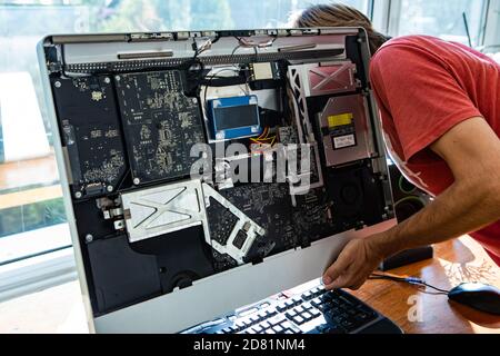 Un technicien informatique de sexe masculin répare un ordinateur de bureau argenté cassé lors de l'ouverture ses pièces et analyse et compréhension du problème Banque D'Images