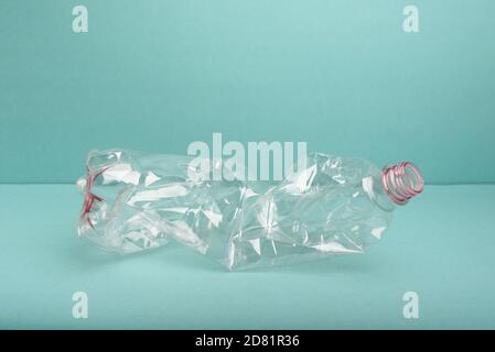 Bouteille en plastique écrasée utilisée sur fond bleu. Banque D'Images