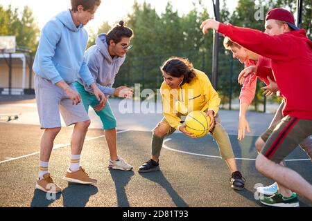 les joueurs de basket-ball en plein air. vacances d'été, vacances, jeux et concept d'amitié. les adolescents caucasiens dans les sweats à capuche décontractés engagés dans le sport, le mode de vie sain, concept de jeunesse Banque D'Images