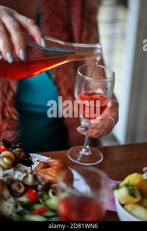 La main de la femme verse du vin rouge d'une bouteille dans un verre Banque D'Images