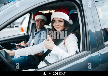 Jeune femme montrant le pouce vers le haut. Joyeux Noël et bonnes cours de conduite du nouvel an pendant les vacances d'hiver. Une étudiante et une enseignante à santa Hats smili Banque D'Images