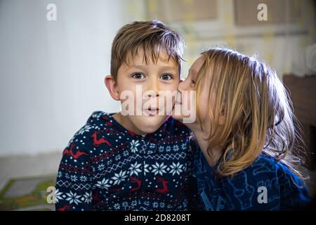 Deux frères et sœurs en pyjama avec livre, soeur baiser frère, drôle émotions énorme maison Banque D'Images