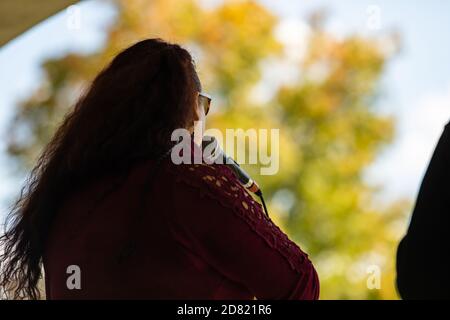Vue arrière de la belle jeune femme tendance portant des lunettes de soleil tenant mic tout en chantant et en se interprétant dans la fête culturelle Banque D'Images