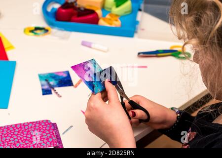 adorable fille avec des papiers colorés, des ciseaux, de la colle, des pailles, des crayons, des rubans, de la dentelle sur la table makint cartes de noël uniques Banque D'Images