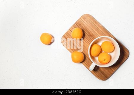 Composition abricot avec bureau en bois sur fond de béton blanc. Bannière Web culinaire. Mise à plat. Espace pour le texte. Placer pour le texte Banque D'Images