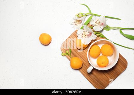 Composition abricot avec bureau en bois, fleurs blanches sur fond de béton blanc. Bannière Web culinaire. Mise à plat. Espace pour le texte. Placer pour le texte Banque D'Images