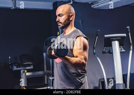 Entraînement sportif de jeune homme dans la salle de gym avec haltères Banque D'Images