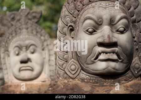 Gros plan des statues d'Asura (démons) dans une rangée à l'entrée sud du temple de Bayon à Siem Reap, Cambodge Banque D'Images