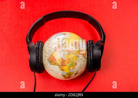 Micro-casque sur globe isolé sur le rouge Banque D'Images