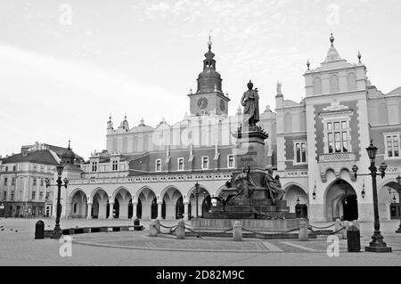 Photo en début de matinée en noir et blanc de la place du marché principal déserte avec le marché en tissu et le monument Mickiewicz dans la vieille ville de Cracovie, en Pologne. Banque D'Images