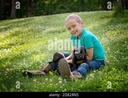 Jeune garçon avec Black Lab Puppy sur l'herbe Banque D'Images