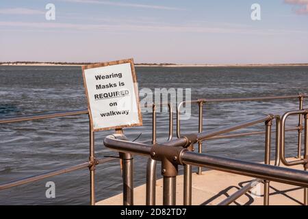 des masques d'usure sont requis sur le panneau de la passerelle derrière une feuille De plastique transparent à la jetée du phare de Barnegat à New Jersey avec vue sur l'eau derrière Banque D'Images