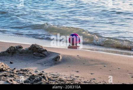 Le volley-ball rose et bleu risque de se laver, car il repose sur les rives du lac Michigan Banque D'Images