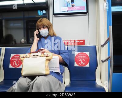 Moscou. Russie. 13 octobre 2020. Une femme dans une voiture de métro parle sur un smartphone. Un masque de protection est sur le visage de la femme. Inscriptions dans Banque D'Images
