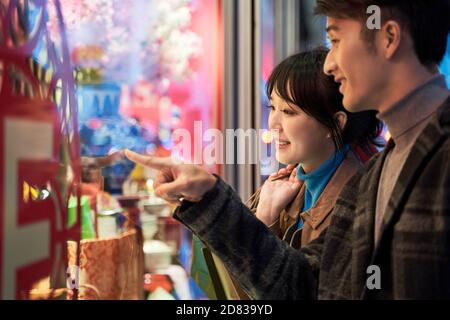 un jeune couple asiatique aimant regarde la fenêtre du magasin et parle heureux et souriant Banque D'Images