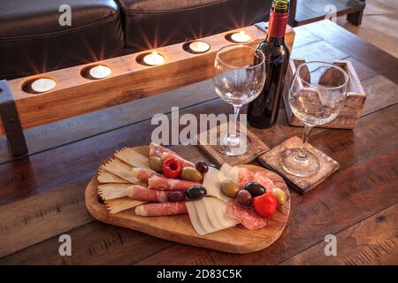 Vin rouge avec Charcuterie sur bois rustique avec bougies derrière une étendue de prosciutto panino, fromage mozzarella, salami de Gênes, fromage Fontina et Banque D'Images