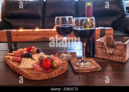Vin rouge avec Charcuterie sur bois rustique avec bougies derrière une étendue de prosciutto panino, fromage mozzarella, salami de Gênes, fromage Fontina et Banque D'Images