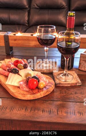 Vin rouge avec Charcuterie sur bois rustique avec bougies derrière une étendue de prosciutto panino, fromage mozzarella, salami de Gênes, fromage Fontina et Banque D'Images