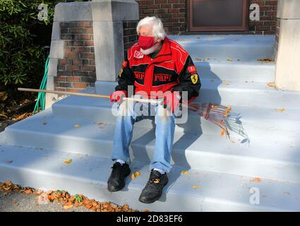 Homme senior assis sur les escaliers avec masque sur tout en tenant un râteau. Banque D'Images