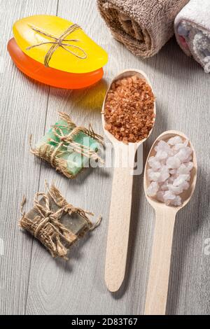 Wooden spoons with white and brown sea salt and handmade soap for bathroom procedures with towels. Spa products and accessories Banque D'Images