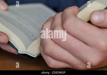 Le livre est entre les mains en gros plan. Livre épais en pastille dure dans les mains des hommes. Concept de lecture et d'auto-éducation Banque D'Images