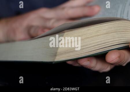 Le livre est entre les mains en gros plan. Livre épais en pastille dure dans les mains des hommes. Concept de lecture et d'auto-éducation Banque D'Images