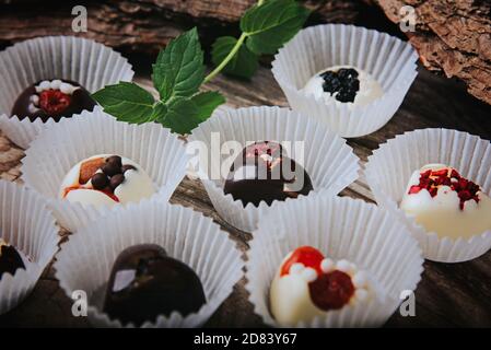 Truffes artisanales au chocolat sur fond de bois. Chocolats faits à la main avec fruits secs. Banque D'Images